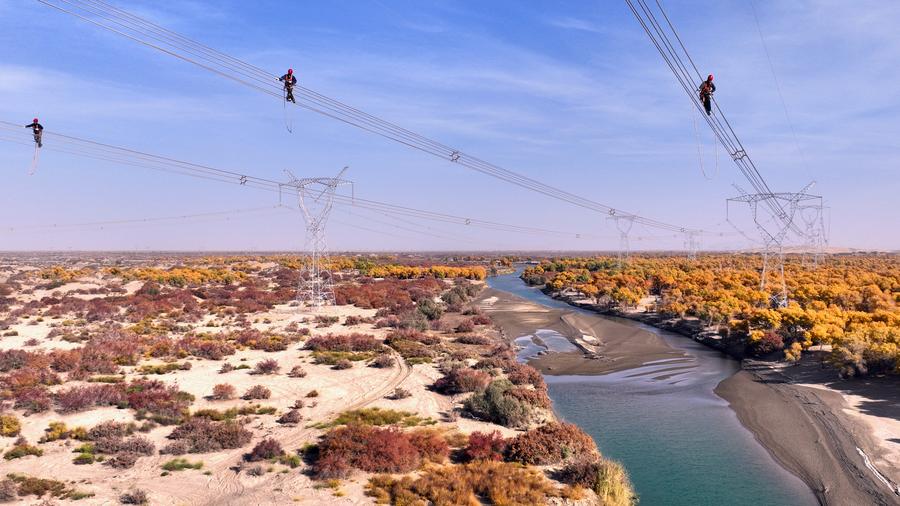 16 اکتوبر 2024 ۔ شمال مغربی چین کے سنکیانگ ویغور خود اختیار علاقے میں 750 کے وی کی پاور ٹرانسمیشن لائن پر کام کرتے ہوئے تکنیکی ماہرین ۔ (تصویر: ما یوان/شین ہوا)
