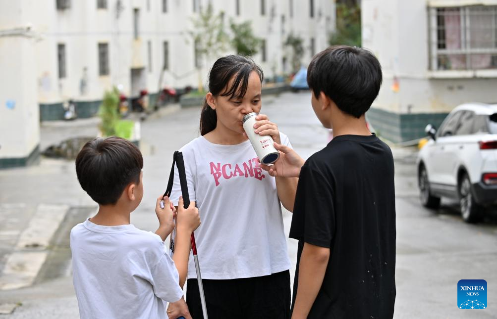 14 اکتوبر 2025۔ گوانگ شی جوانگ خود اختیار علاقے کی فنگ شان کاونٹی میں، لان یی جین اپنے بیٹوں کے ساتھ چہل قدمی کے دوران ایک جگہ رک کر پانی پی رہی ہیں۔ (شنہوا/لوبوآن)