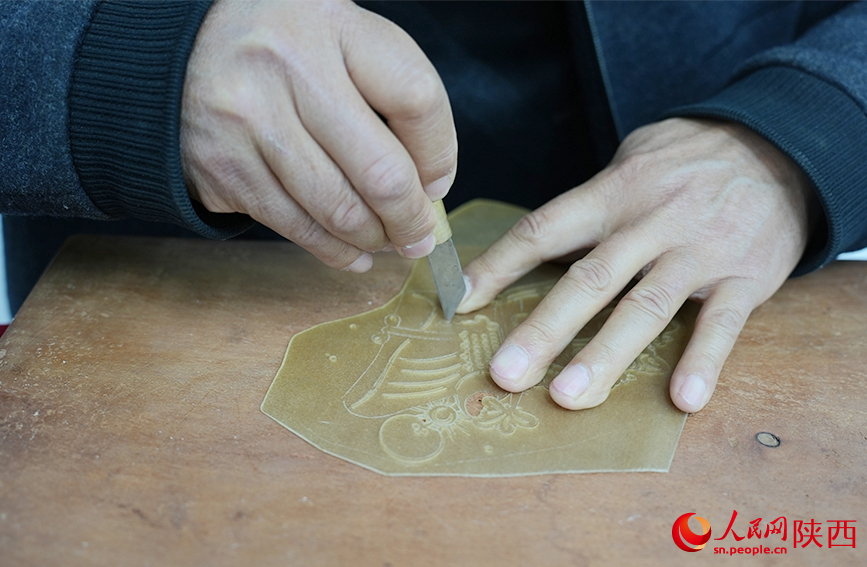 شمال مغربی چین کے صوبے شائنشی کے گاؤں شوانگ چوان میں ، شیڈو  کٹھ پتلی کے فن کا  مورث چھین یی ون، ایک کھال پر پتلی کا خاکہ  تراش رہا ہے۔(پیپلز ڈیلی آن لائن۔سون تھنگ )